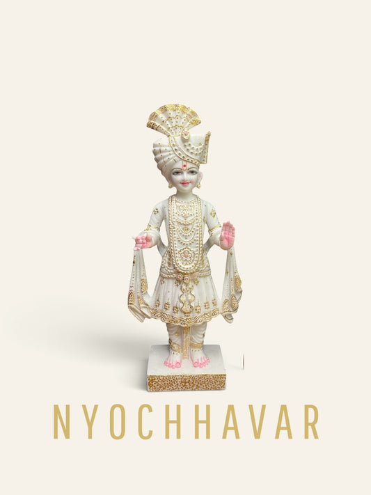 White marble Swaminarayan murti with gold detailing on the turban and robes, standing with raised hand